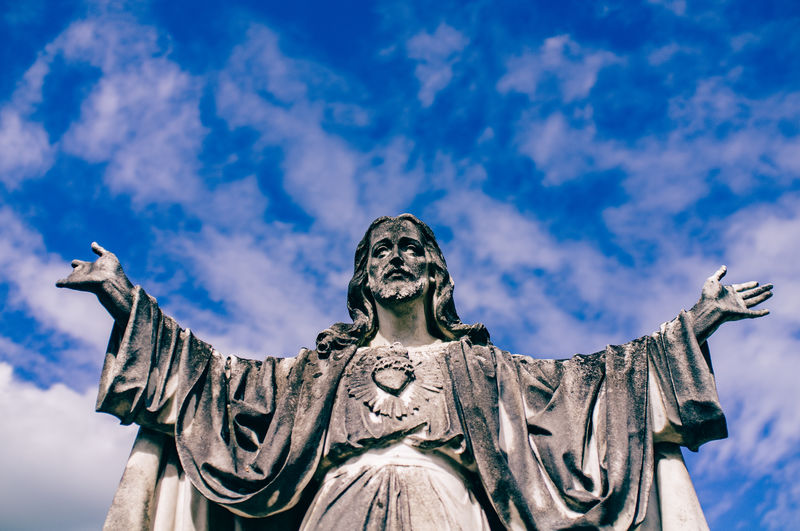 Low angle view of jesus statue against blue sky