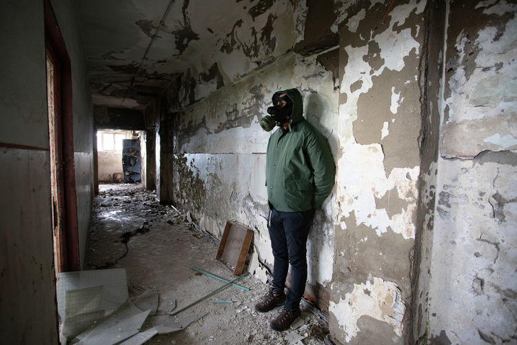 Man wearing gas mask standing in abandoned building
