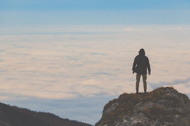 Rear view of man looking at mountain against sky