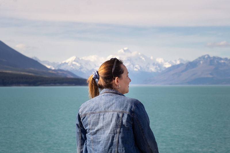 Girl contemplating view of the famous snow-capped mt. cook across lake pukaki on a sunny day.