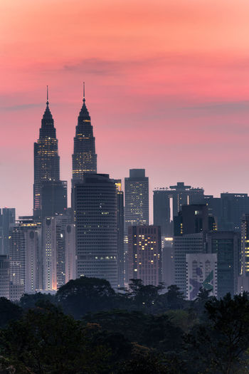 Illuminated buildings in city against sky during sunset