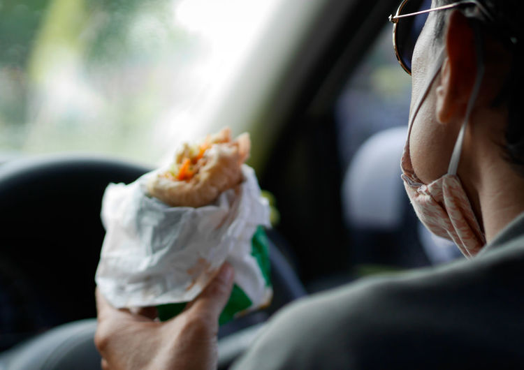 Midsection of woman eating burger at car