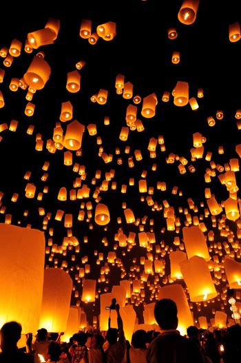 Low angle view of illuminated lanterns hanging against sky at night