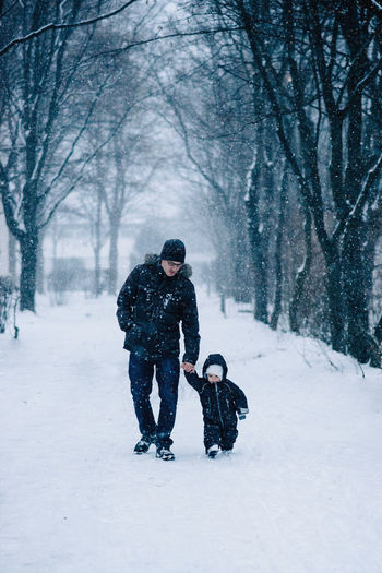 Full length of father walking with daughter on snow covered land during winter