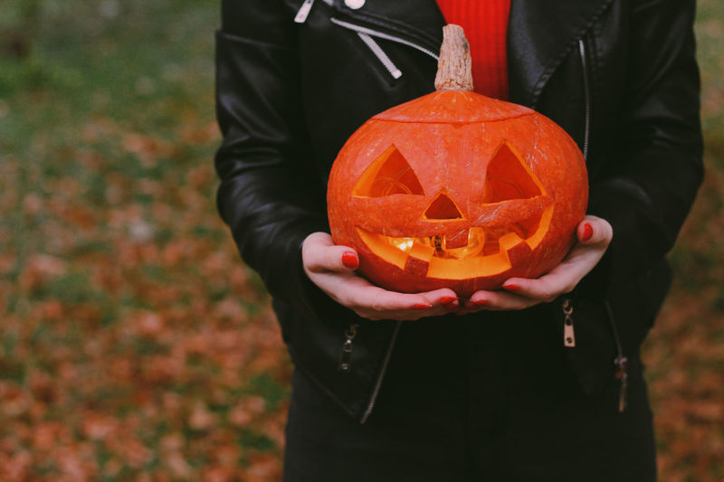 Girl holding jack-o-lantern. carved halloween spooky pumpkin.