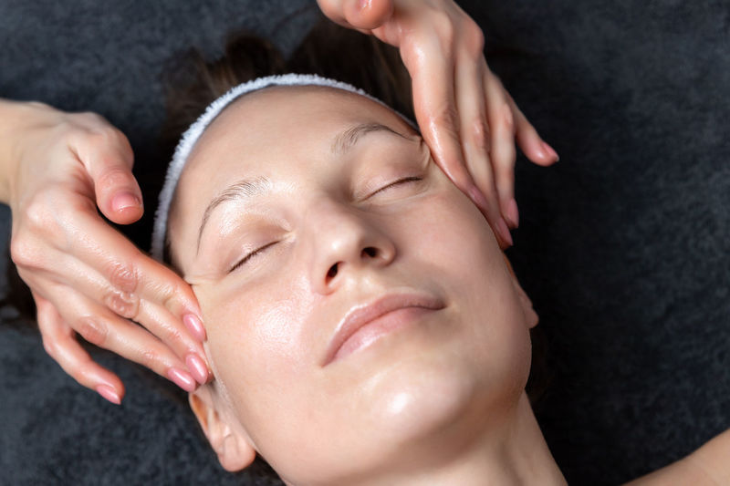 Close-up portrait of woman lying on hand