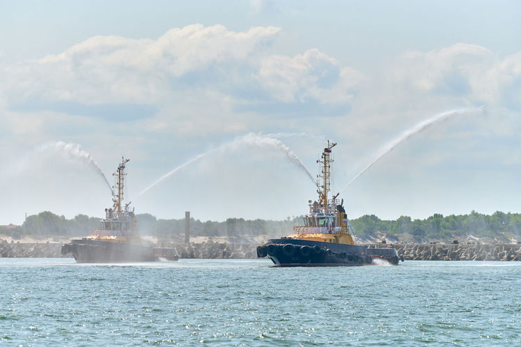 Floating tug boats spraying jets of water, demonstrating firefighting water cannons. fire boats