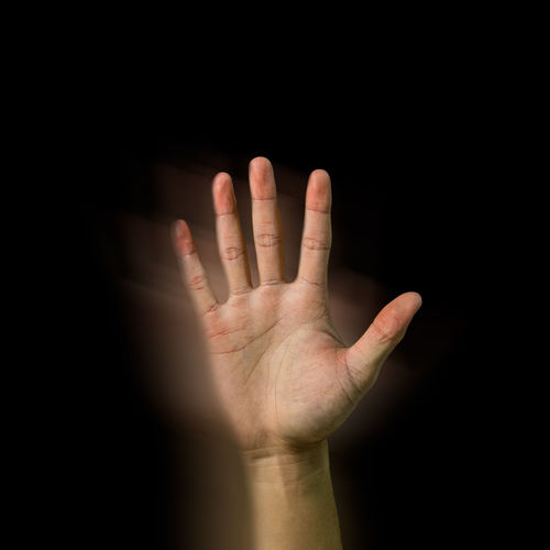 An asian hand raised on black background showing his palm