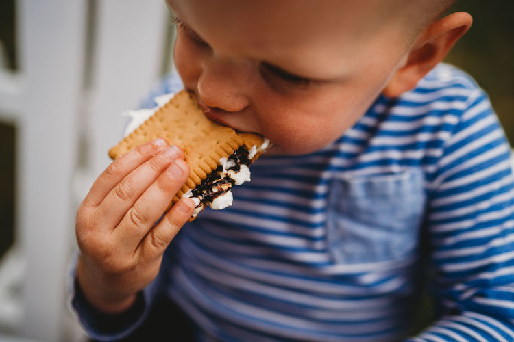 Close up of young boy eating cookies and marshmallows smores