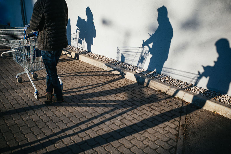 Rear view of shadow of people pushing shopping cart 