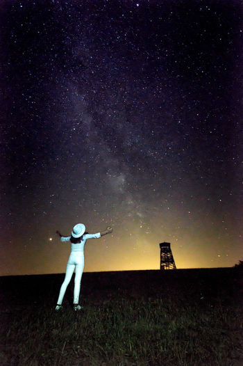 Full length rear view of girl standing against star field at night