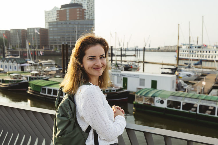 Smiling woman standing at port of hamburg, germany