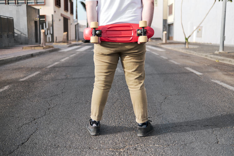 Unrecognizable young man with red skateboard in the street
