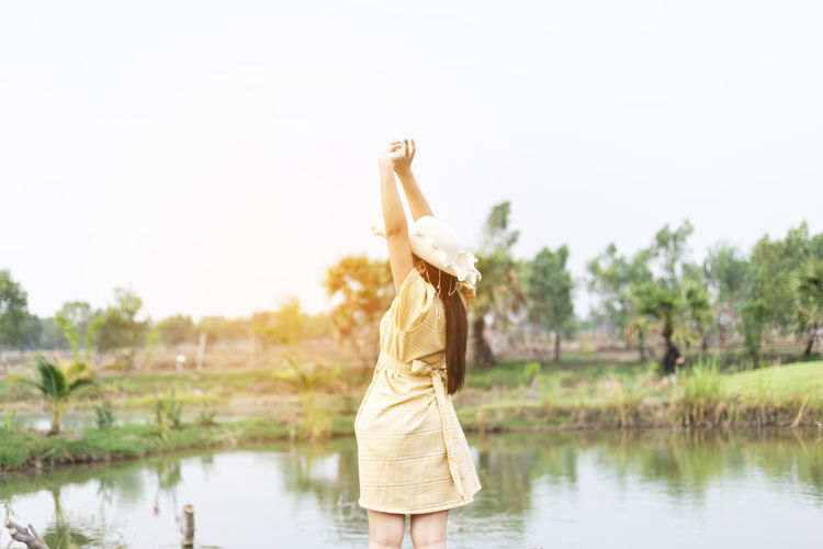 Woman standing by lake against sky