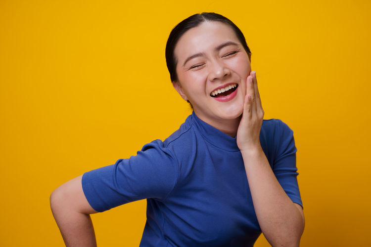 Portrait of a smiling young woman over yellow background