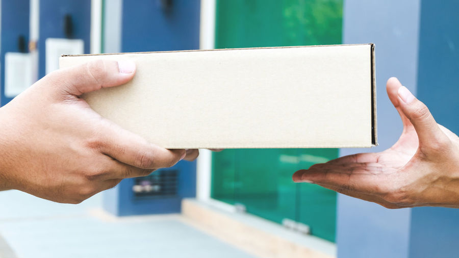 Cropped hands of delivery person giving box to customer