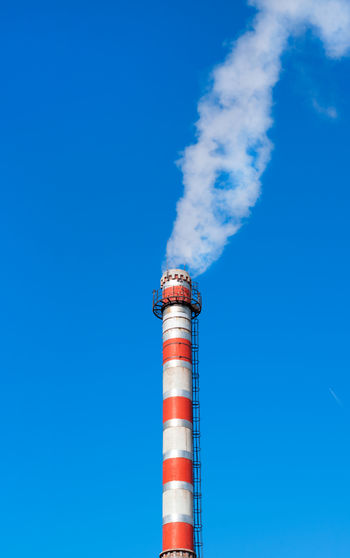Factory chimney releasing steam against the clear blue sky