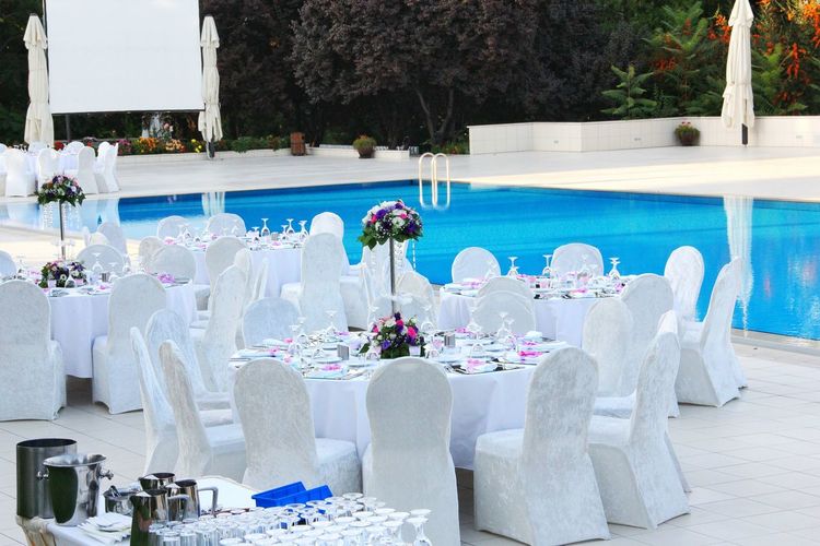 Tables and chairs arranged by swimming pool at resort