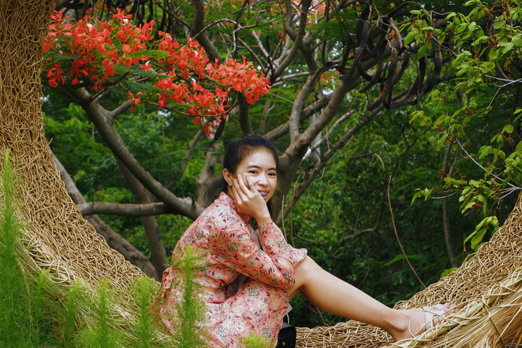 Portrait of smiling young woman standing by plants