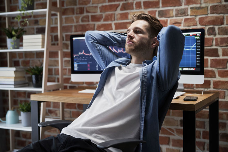 Young man looking away while resting at office