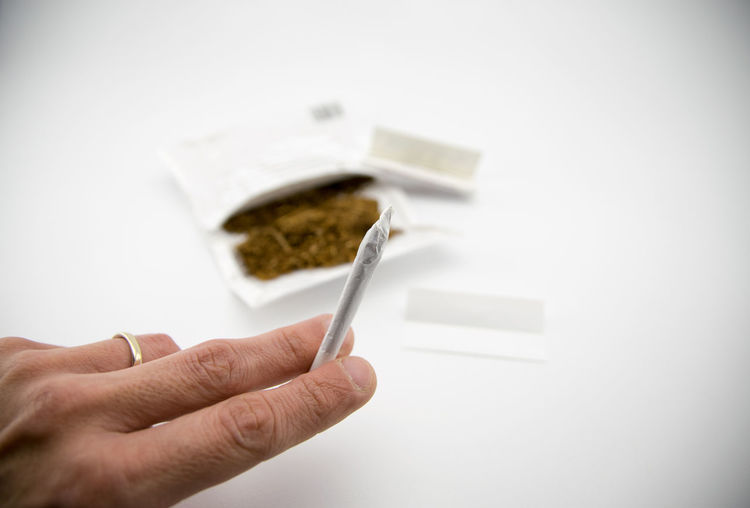 Close-up of hand holding marijuana joint on table