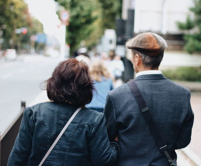 Rear view of couple walking on sidewalk in city
