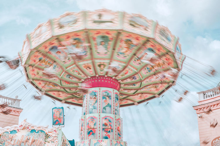 Low angle view of spinning carousel against sky