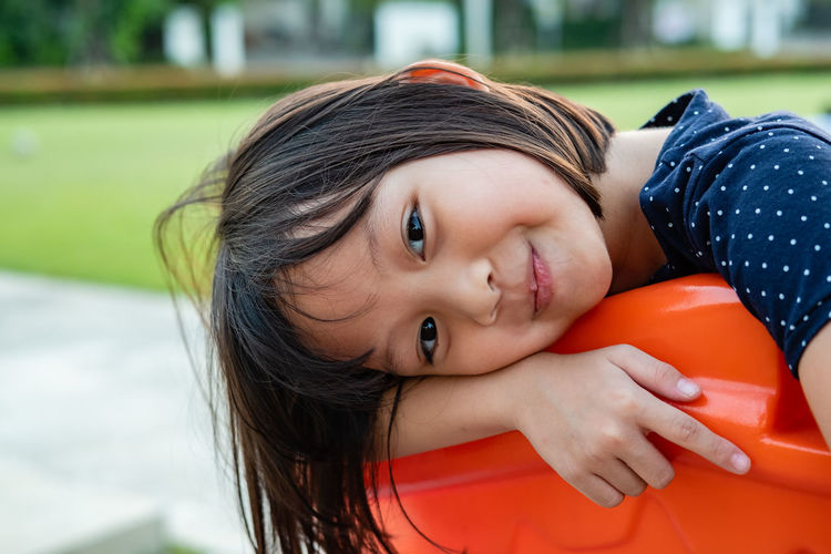 Portrait of cute smiling girl sitting on outdoor play equipment in park