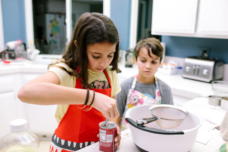 Girl measures baking soda while boy watches