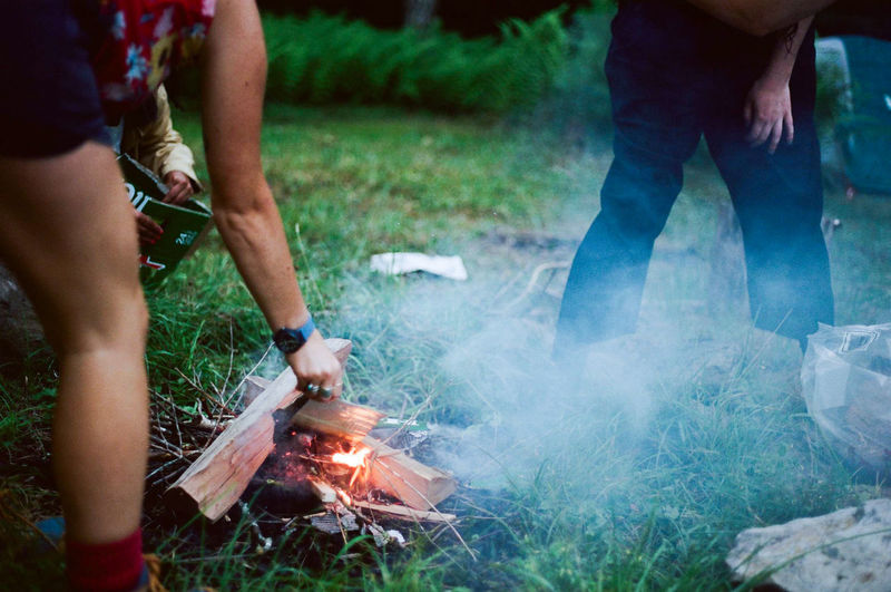Friends making campfire on grassy field