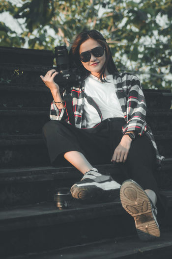 Young woman wearing sunglasses sitting outdoors