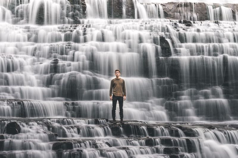 Portrait of man standing against waterfall