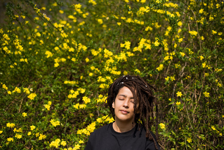 Portrait of woman with locs shot against flower background