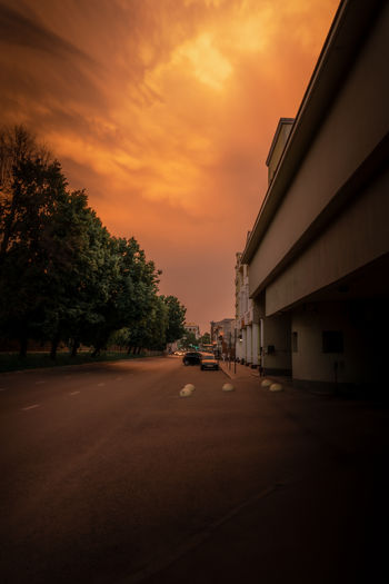 Street amidst buildings against sky during sunset