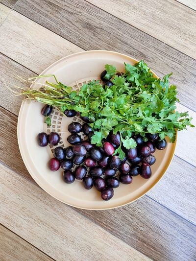 High angle view of plum and coriander in bucket