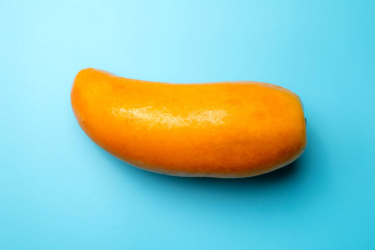 Close-up of orange apple against blue background