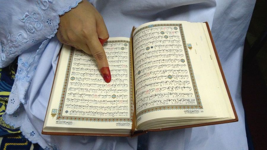 Midsection of woman reading koran