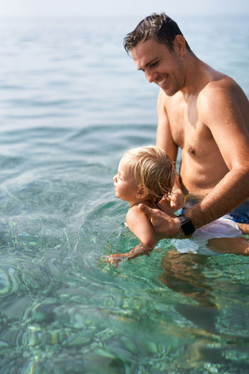Portrait of shirtless man swimming in sea