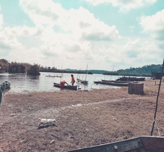 People sitting on beach by lake against sky