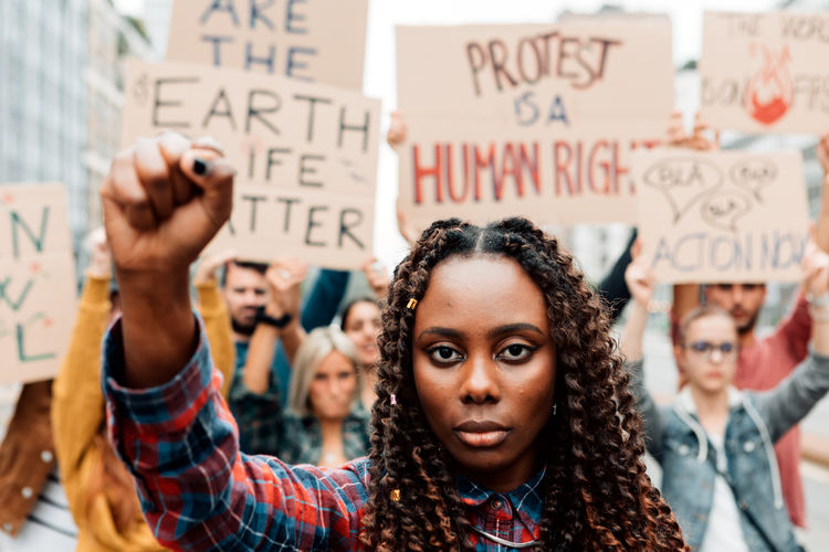 African woman with clenched fist in climate strike - group of militants protest for global warming