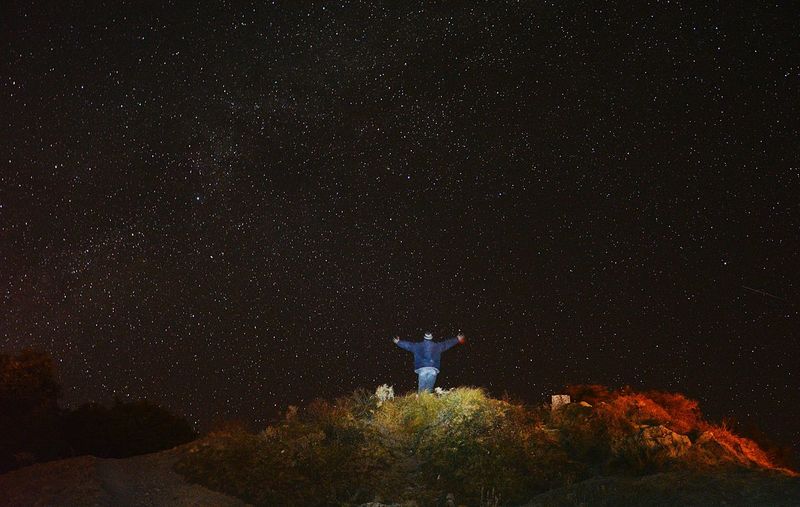 Low angle view of man standing against star field at night