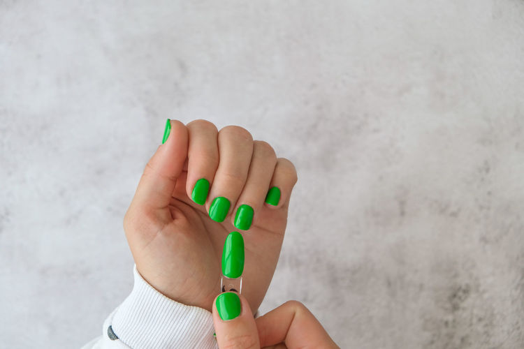 Manicured female hands with stylish green nails. trendy modern design manicure. gel nails. skin care