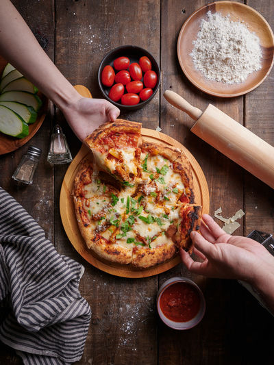 Cropped hand of person preparing pizza on table