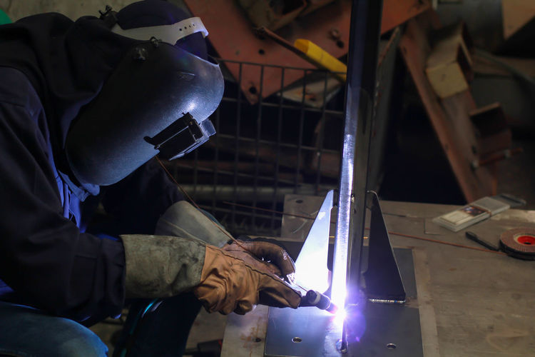 Side view of worker welding metal in workshop
