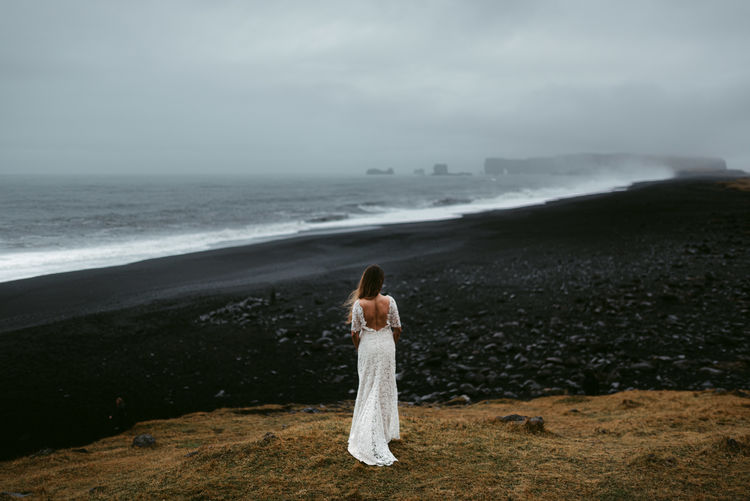 Woman standing on beach against sky