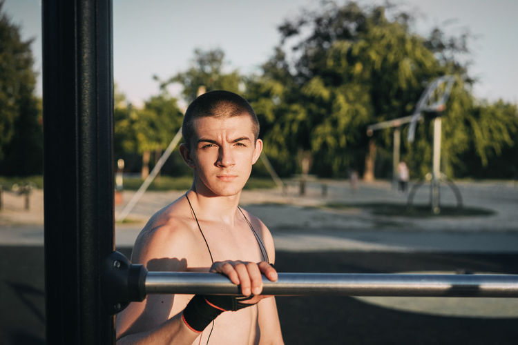 Portrait of shirtless man standing by railing