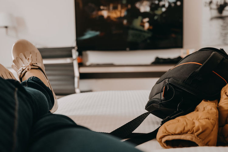Low section of person watching tv while relaxing on bed at home