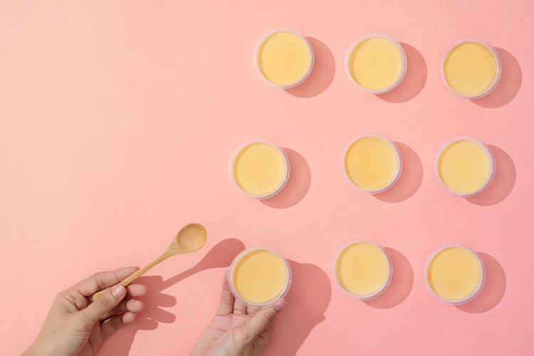 Hand putting creme caramel in minimalist style setup on pink background