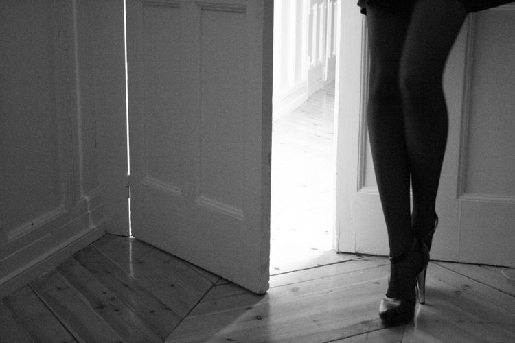 Low section of seductive woman standing by doorway at home
