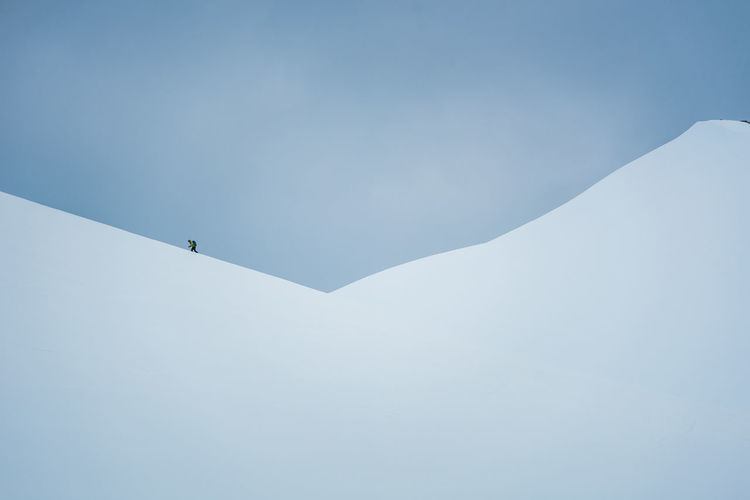 A man hikes up a snowy hill on skis